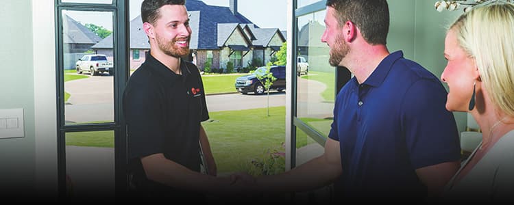 A man and woman are at the front door greeting a Trane dealer.