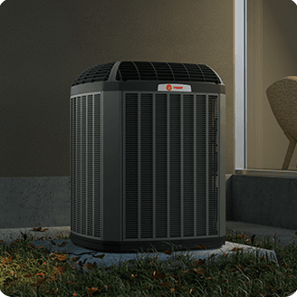 A Trane air conditioner is sitting outside of a home.