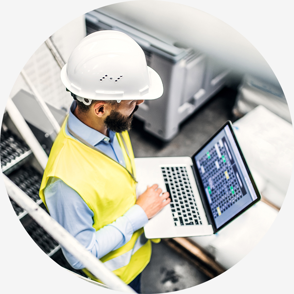 A portrait of an industrial man engineer with laptop in a factory, working.