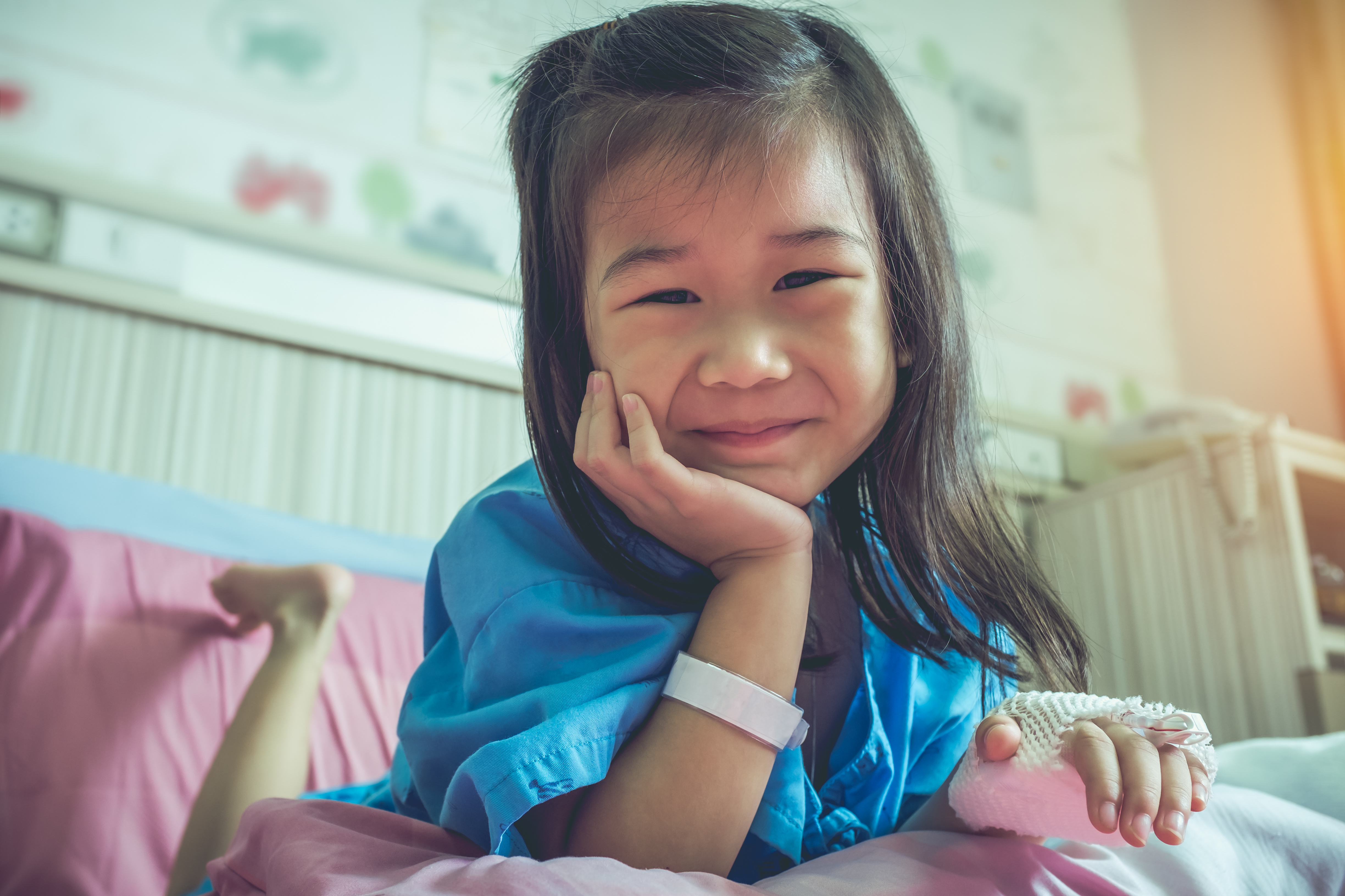 Illness asian child admitted in hospital with saline iv drip on hand. 