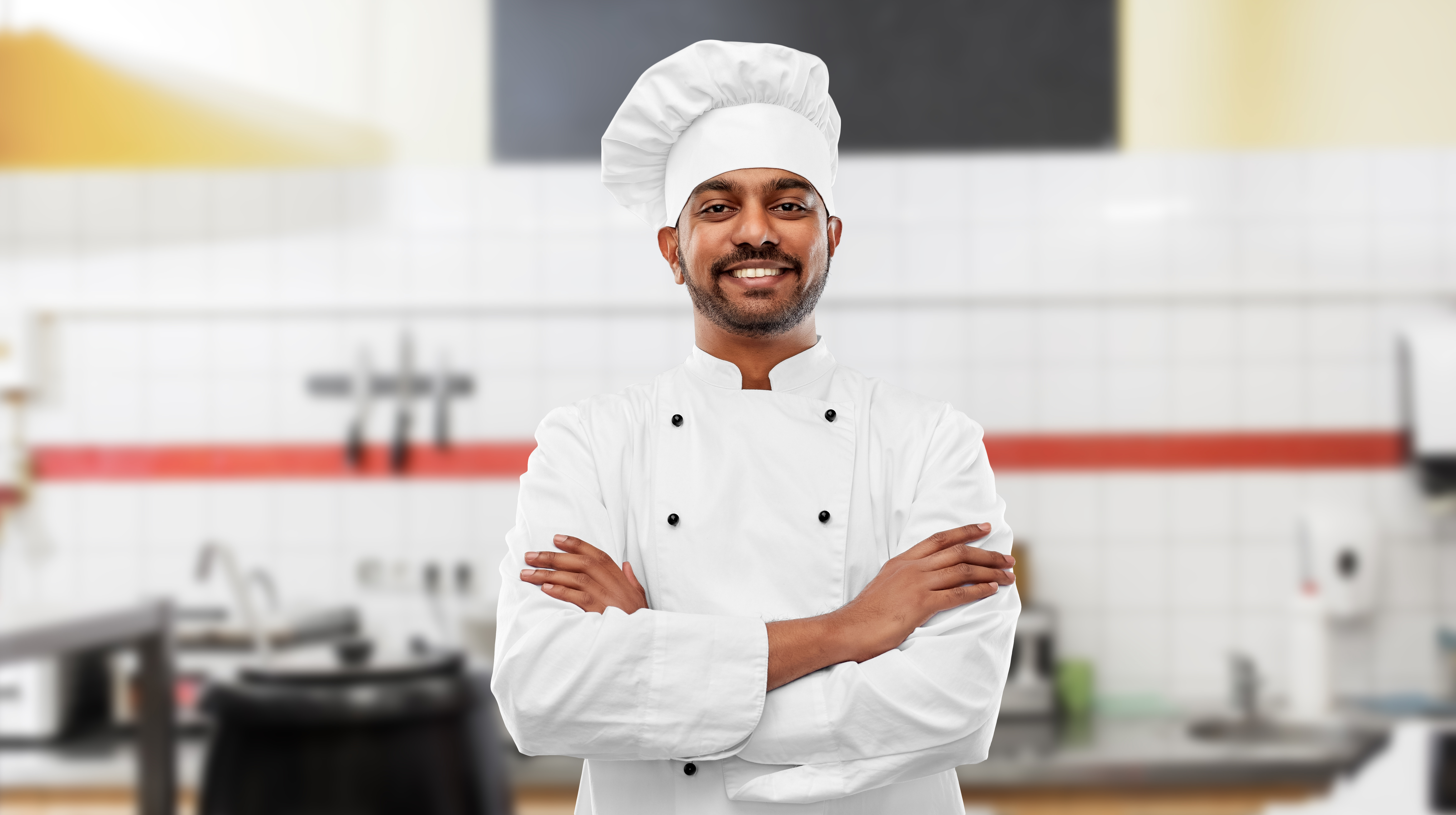 happy indian chef in toque at restaurant kitchen