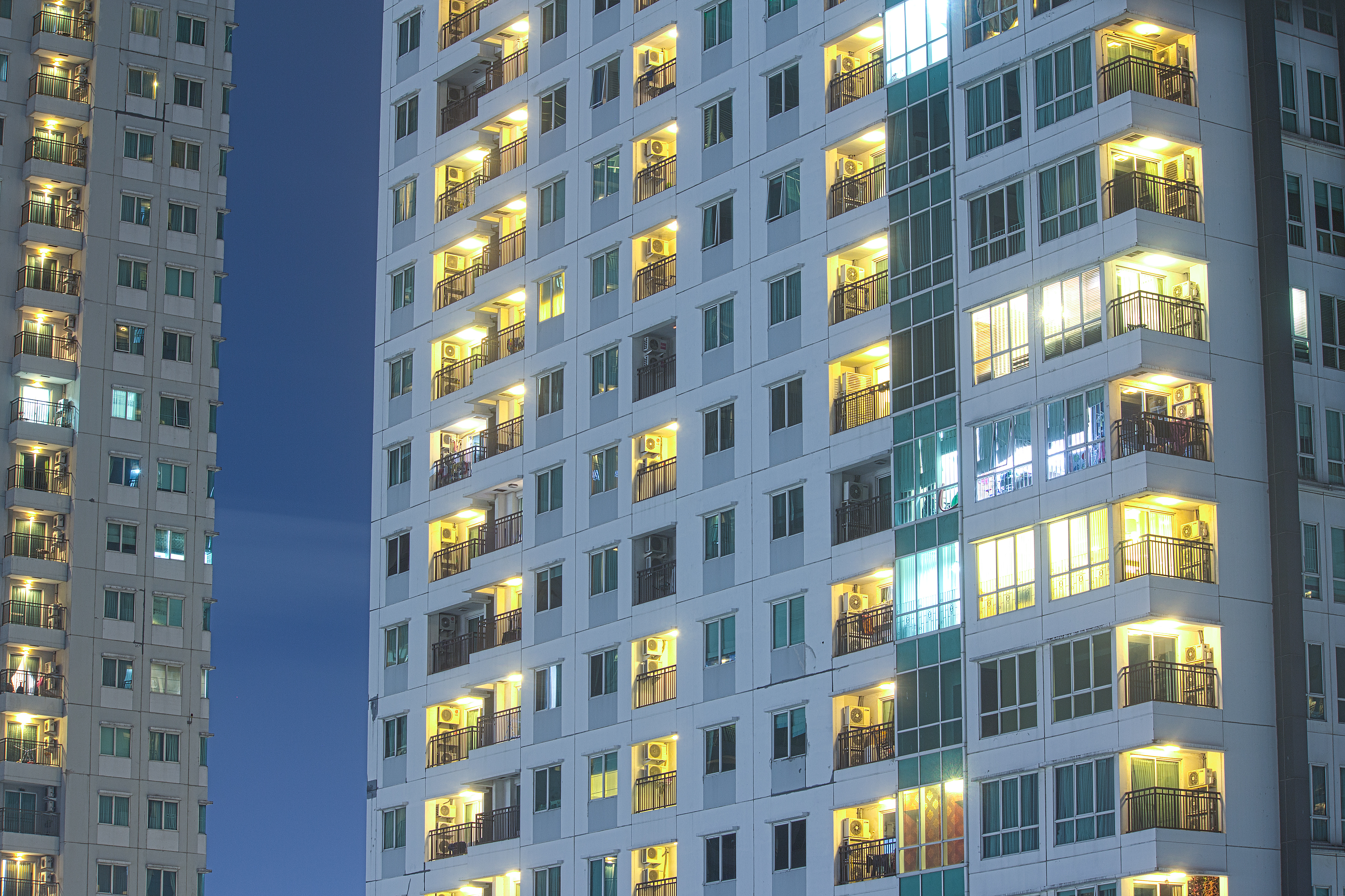 Priivacy concept in highrise apartment windows at night lit in cityscape urban highrise buildings.  Apartment towers for home property and rental.