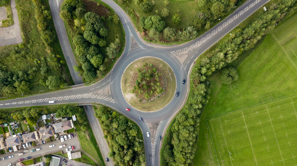 Top down aerial view of a traffic roundabout on a main road in an urban area of the UK