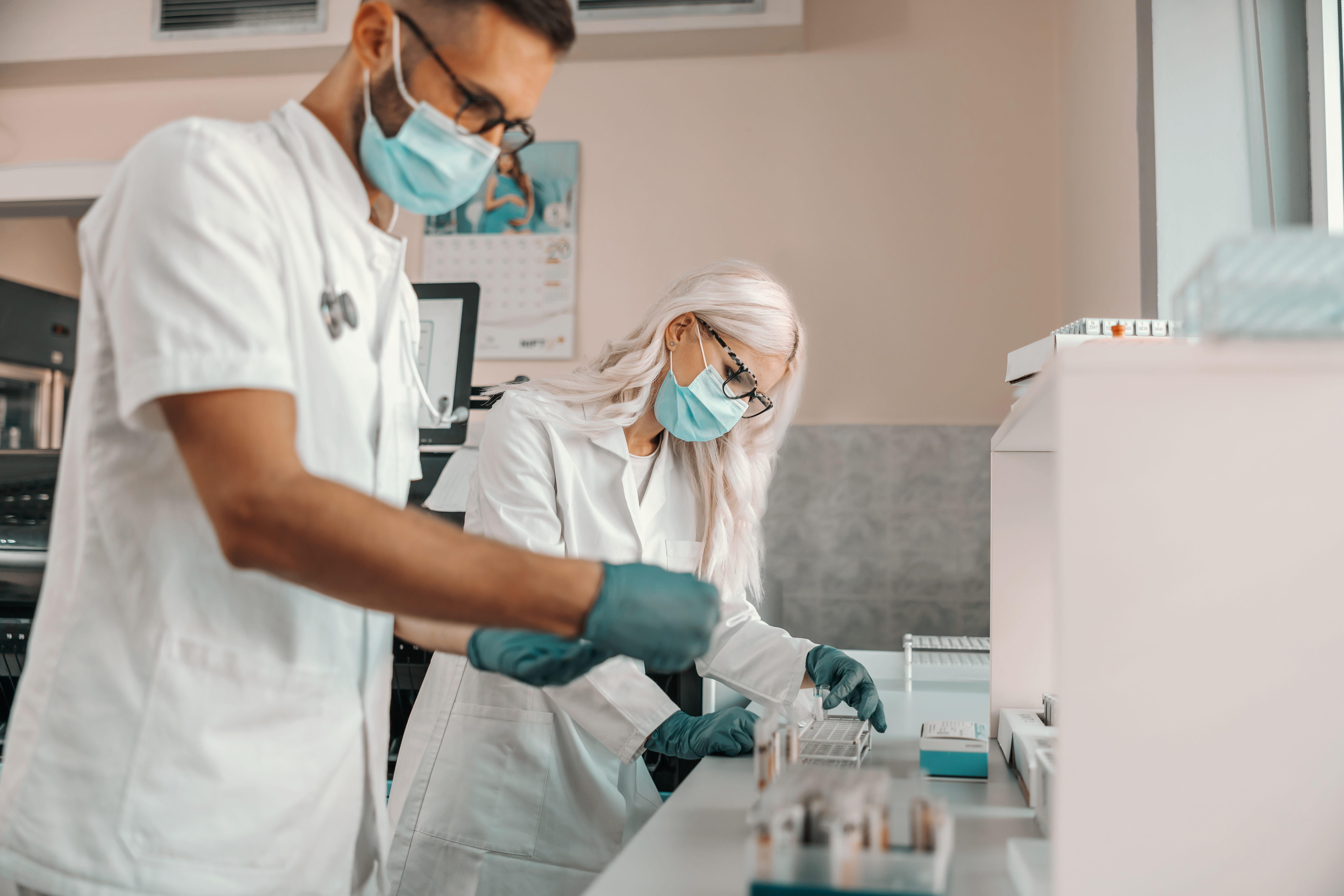 Two hardworking medial workers holding test tubes with blood samples and working on cure for dangerous disease.