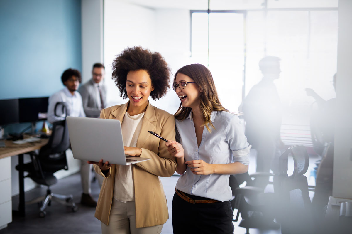 Happy smiling business women working together online on a laptop in office