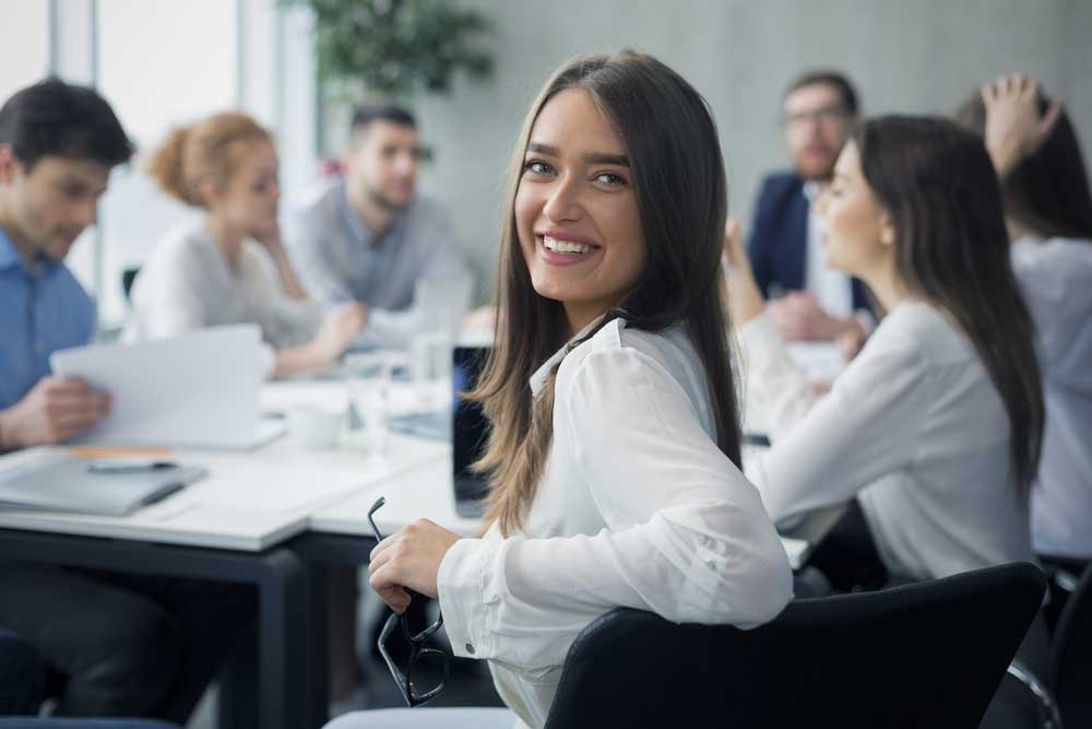 Positive secretary smiling to camera during meeting